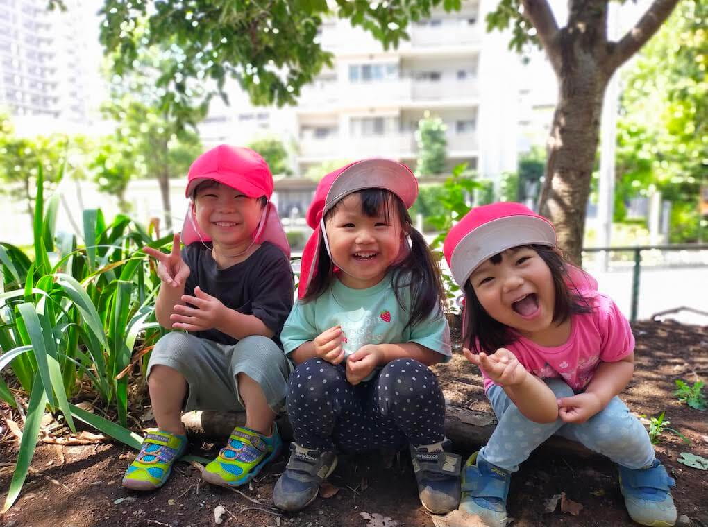 屋外の花壇に座って笑顔を見せる子どもたち