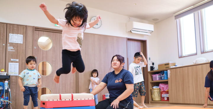保育士のサポート受けながら園児たちが運動する様子