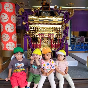 園児たちが神輿の前に座ってこちらを向く様子