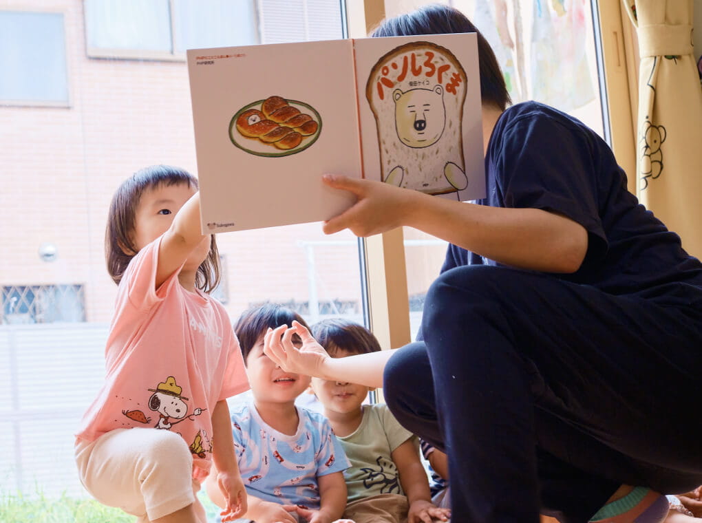 保育士が園児たちに絵本を読み聞かせる様子