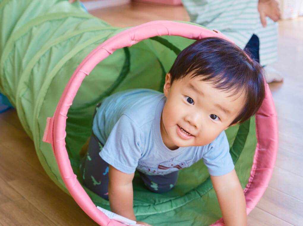 筒の中をくぐり抜けて遊ぶ園児