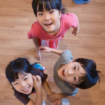 園児たち3人が上を向き、それを真上から見た様子