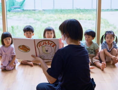 保育士が園児に絵本を読み聞かせる様子
